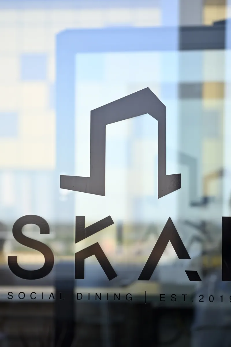 SKAI:s märke i guld på glasväggen mot matsalen