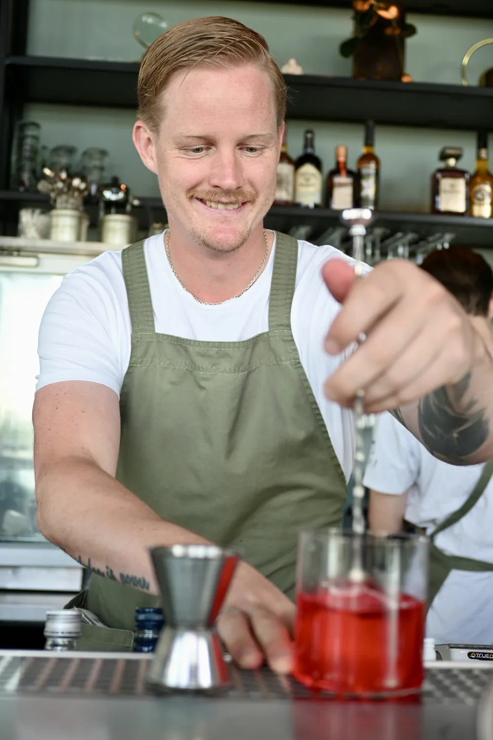 Bartendern häller upp en röd cocktail i baren på SKAI